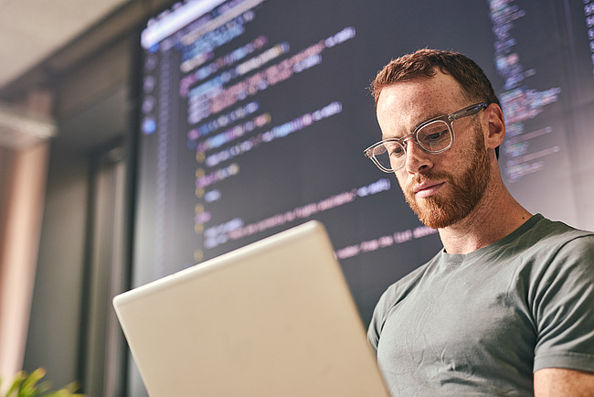 Krypto: Bankfachmann sieht sich Programmcode auf dem Laptop an Krypto: Bankfachmann sieht sich Programmcode auf dem Laptop an